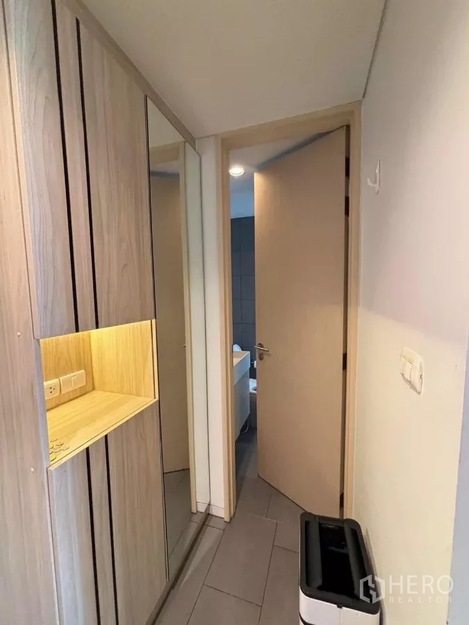Condominium for rent or sale in Phaya Thai, Bangkok - Corridor with mirrored cabinet and door leading to a tiled bathroom.