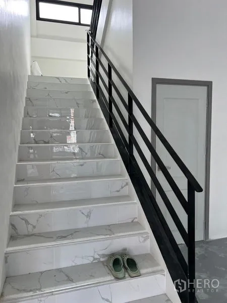 Warehouse for rent in Bang Sao Thong, Samut Prakan - Staircase with marble-look tiles and a black handrail leading to upper office levels.