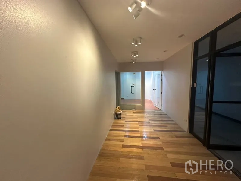 办公空间 出租在Yan Nawa, Bangkok - 木地板走道，射灯照明，玻璃门通向各房间。
