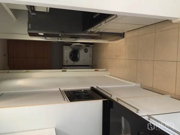 公寓 出租或出售在Pathum Wan, Bangkok - 走廊式厨房，白色橱柜、黑色台面、嵌入式烤箱、大冰箱与洗烘一体机。