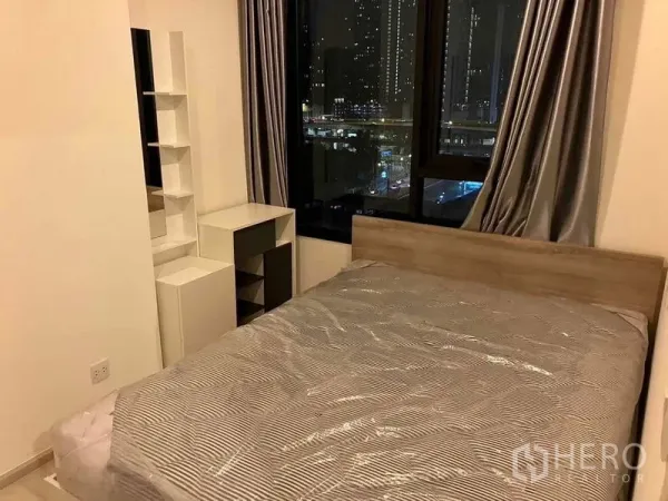 คอนโด ให้เช่าหรือขายในRatchathewi, Bangkok - ห้องนอนเตียงควีน พร้อมชั้นวางบิวท์อินและหน้าต่างบานใหญ่ชมวิวเมืองยามค่ำ