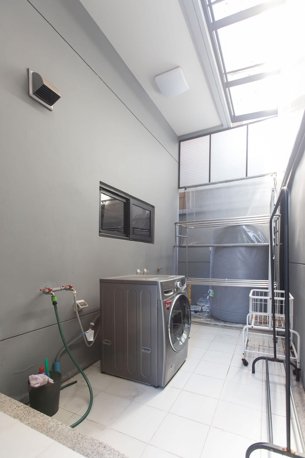 Detached House for rent in Lat Phrao, Bangkok - Laundry zone with front-load washer, utility taps, skylight, and water tank.