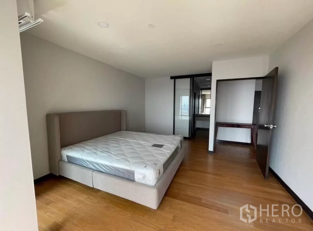 Condominium for rent in Sathon, Bangkok - Bedroom leading toward a dressing area with wood flooring.