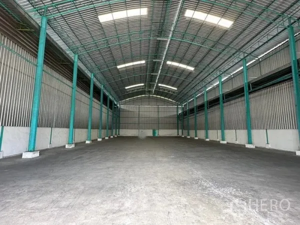 Warehouse for rent in Bang Pa-in, Phra Nakhon Si Ayutthaya - Spacious warehouse interior with high arched roof, green steel columns and concrete floor.