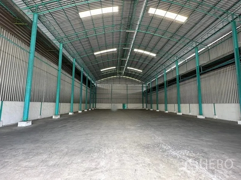 Warehouse for rent in Bang Pa-in, Phra Nakhon Si Ayutthaya - Spacious warehouse interior with high arched roof, green steel columns and concrete floor.