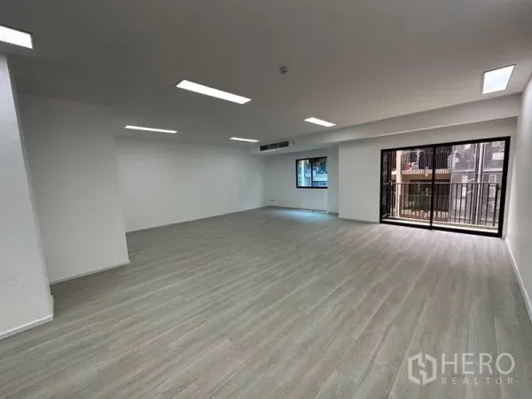 办公空间 出租 - 开放式办公室内，木纹地板、嵌入式LED照明，带窗户与通往小阳台的推拉玻璃门。