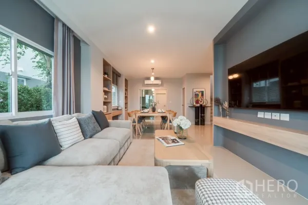 Detached House for rent in Saphan Sung, Bangkok - Open‑plan living and dining room with large sectional sofa, TV wall and warm lighting.