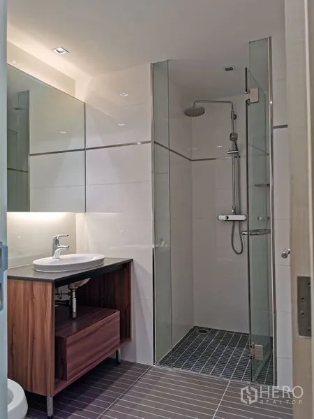 Condominium for rent or sale in Phaya Thai, Bangkok - Compact bathroom with a glass rain shower and sleek vanity.