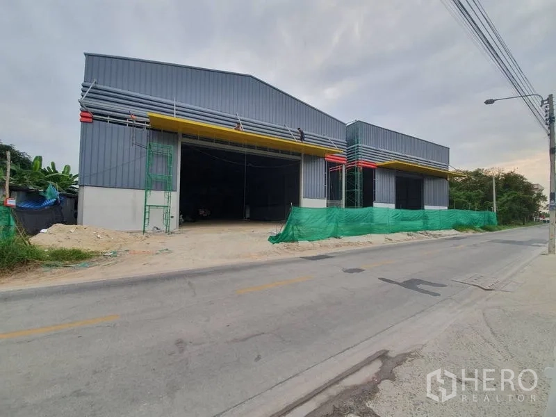 Warehouse for rent in Sai Mai, Bangkok - Street frontage of a new warehouse with large yellow canopies and multiple loading bays.