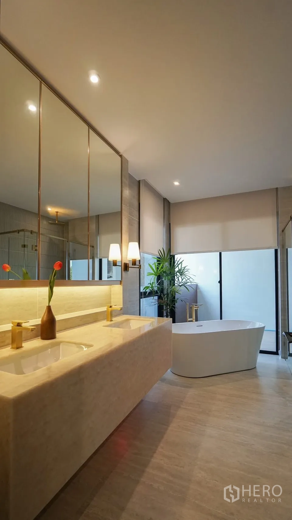 Detached House for rent or sale in Bang Kapi, Bangkok - Elegant bathroom with backlit round mirror, stone vanity and glass shower.
