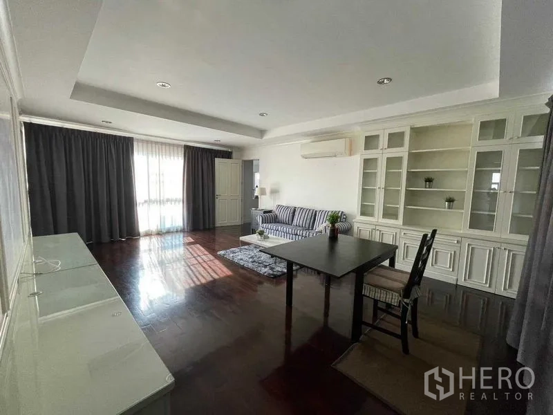 Detached House for sale in Wang Thonglang, Bangkok - Spacious family room with white built-in cabinetry, wood flooring, striped sofa and a table