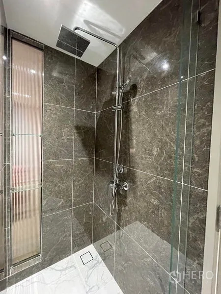 Condominium for rent in Khlong Toei, Bangkok - Glass shower with dark stone tiles and rainfall showerhead