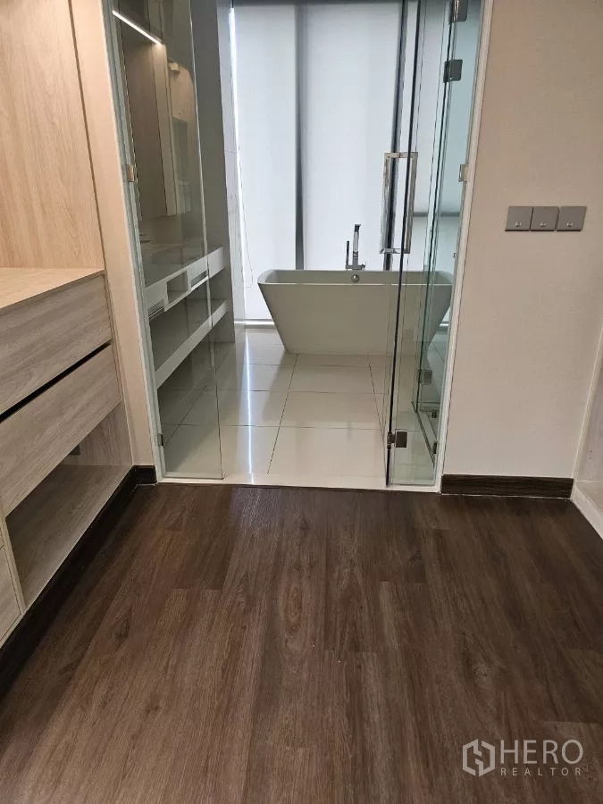 公寓 出租在Watthana, Bangkok - 现代浴室，玻璃门、盥洗台与靠窗的独立式浴缸。