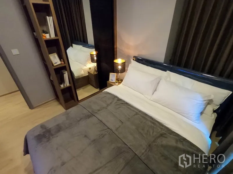 公寓 出租或出售在Watthana, Bangkok - 次卧角落，内置书架、全身镜与整洁铺好的床铺。