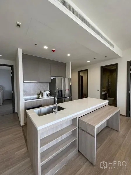 Condominium for rent in Bang Kho Laem, Bangkok - Modern open kitchen with a large quartz island, sink, and wood floors.