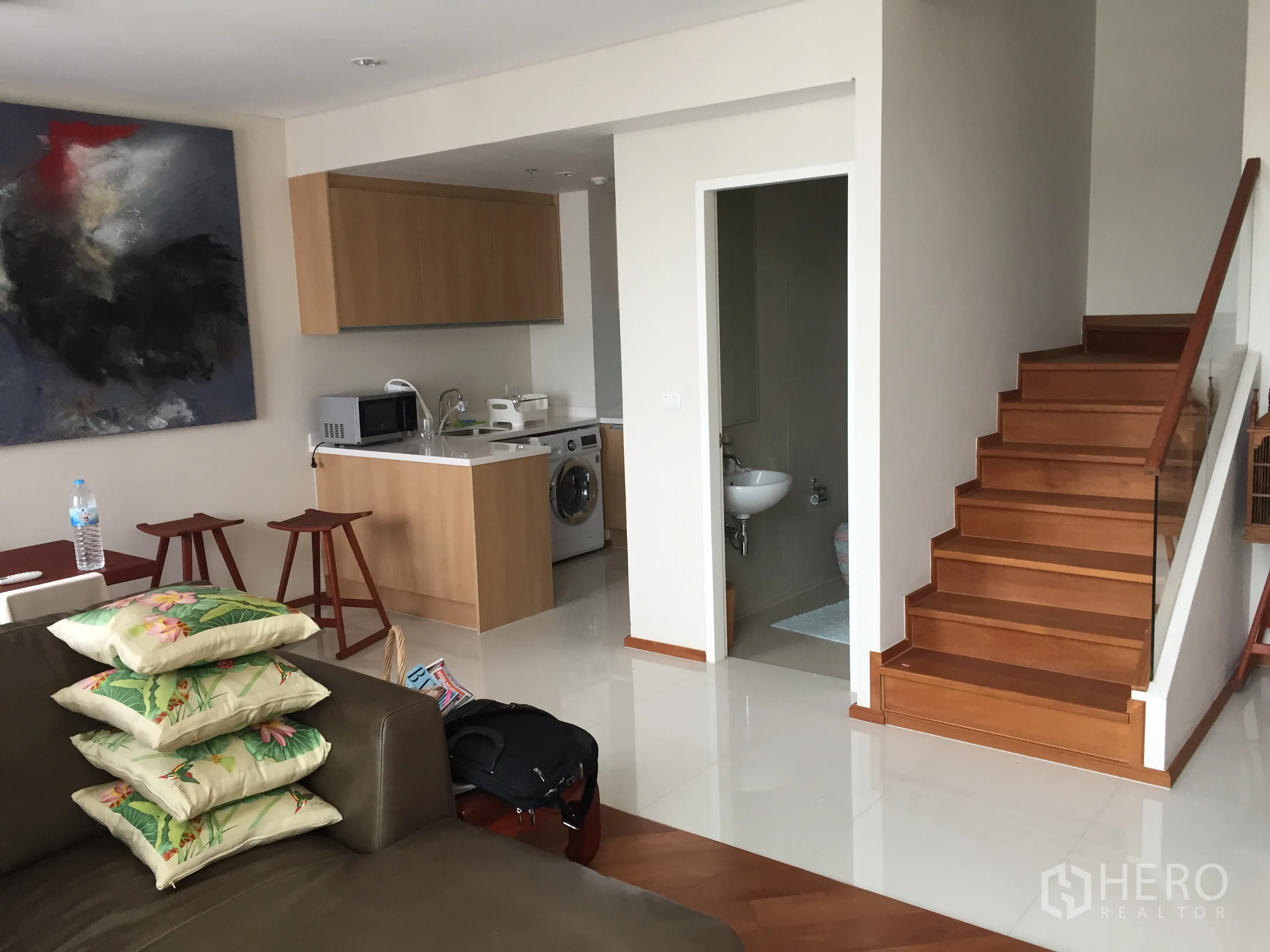 公寓 出租在Ratchathewi, Bangkok - 开放式厨房，木质柜体、微波炉与洗衣机，旁有木楼梯和卫生间。