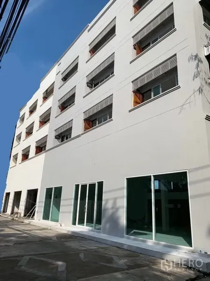 Office Space for rent in Huai Khwang, Bangkok - Modern multi-storey white office exterior with large ground-floor glass doors and a paved forecourt.