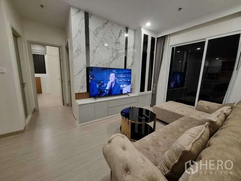 Condominium for rent - Living room with marble feature wall, wall-mounted TV and coffee table.