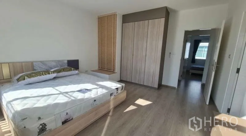 Townhouse for rent in Prawet, Bangkok - Master bedroom with built-in wardrobe, wood flooring and abundant daylight.