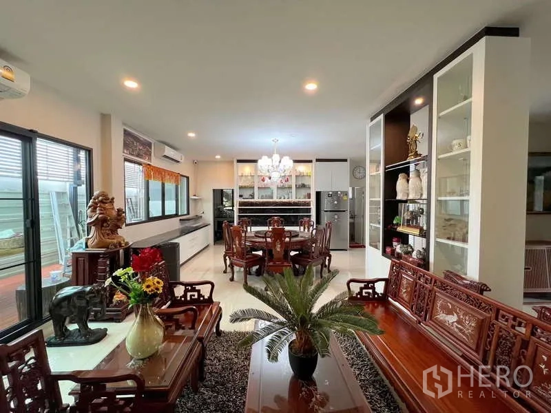 独立式住宅 出售在Prawet, Bangkok - 起居区视角，雕花木沙发、展示柜与通透采光窗。