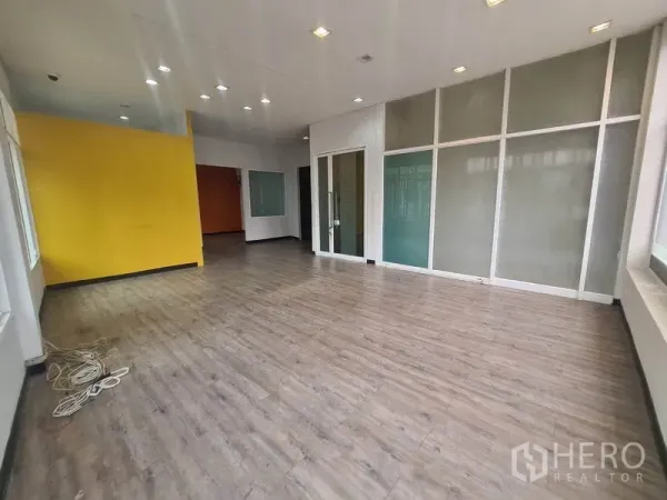 Retail Space for rent in Watthana, Bangkok - Spacious showroom featuring a yellow accent wall, recessed lights, and glass partitions.