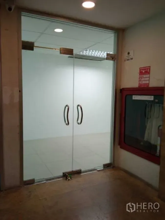 办公空间 出租在Huai Khwang, Bangkok - 走廊处双开玻璃门的办公室入口，旁设消防箱。