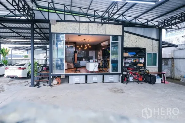 Warehouse for rent in Bueng Kum, Bangkok - Facade of the warehouse showing wide sliding glass doors opening to the office and organized shelving.