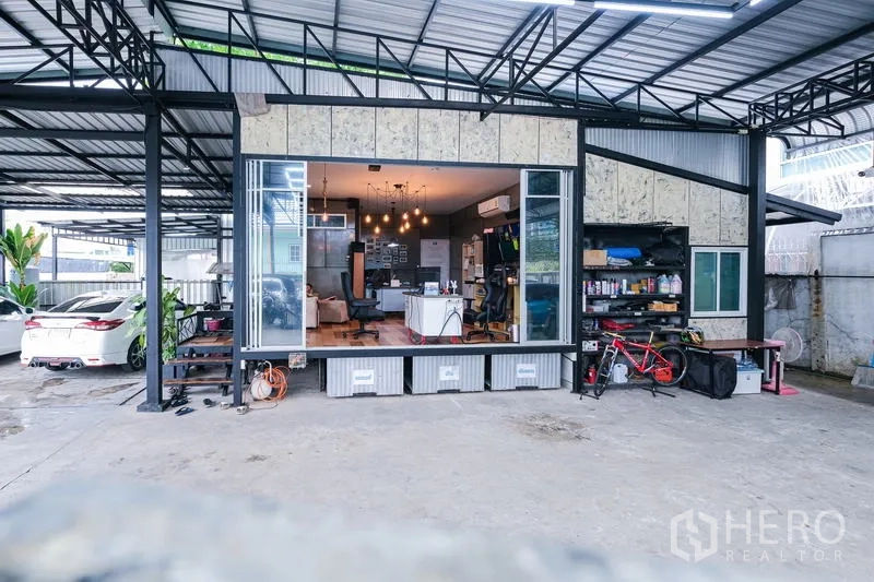 Warehouse for rent in Bueng Kum, Bangkok - Facade of the warehouse showing wide sliding glass doors opening to the office and organized shelving.