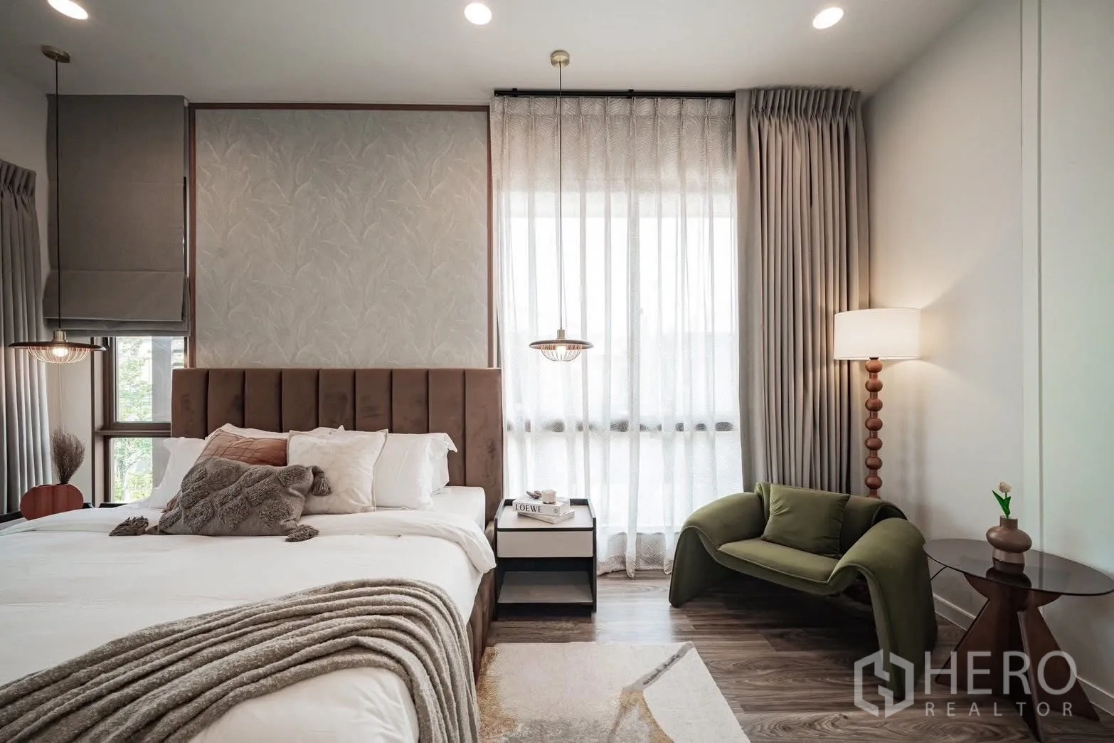 Detached House for sale in Bang Kapi, Bangkok - Bright master bedroom in a Bang Kapi detached house with upholstered headboard, sheer curtains, green lounge chair and bedside table.