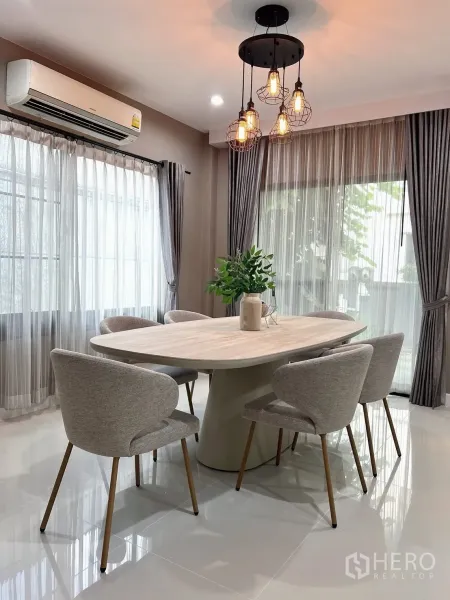 Detached House for rent in Prawet, Bangkok - Dining room with oval table for six under industrial-style pendant lights and big windows.