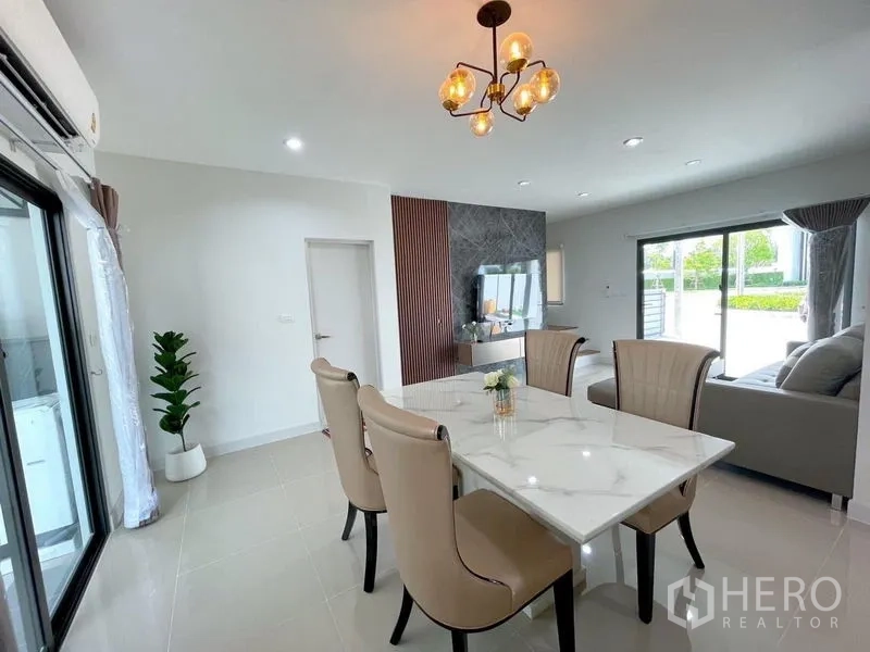 联排别墅 出租在Bang Phli, Samut Prakan - 从餐区望向客厅，大窗引入花园景致与自然光。