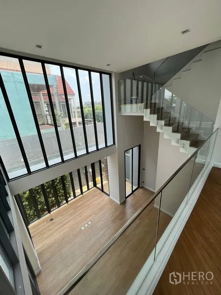 带办公室的家 出售在Wang Thonglang, Bangkok - 挑高夹层空间，玻璃栏杆楼梯与整面落地窗，眺望周边景致。