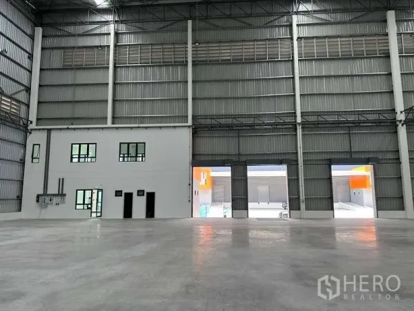 Factory for rent in Bang Phli, Samut Prakan - Warehouse wall with integrated two‑storey office and dock openings to the yard.