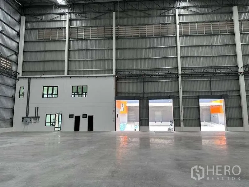 Factory for rent in Bang Phli, Samut Prakan - Warehouse wall with integrated two‑storey office and dock openings to the yard.