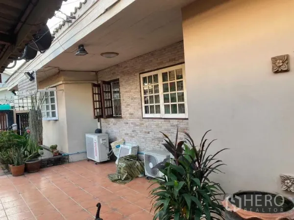 Detached House for sale in Wang Thonglang, Bangkok - Shaded side patio with terracotta tiles, potted plants and exterior air-conditioning units.