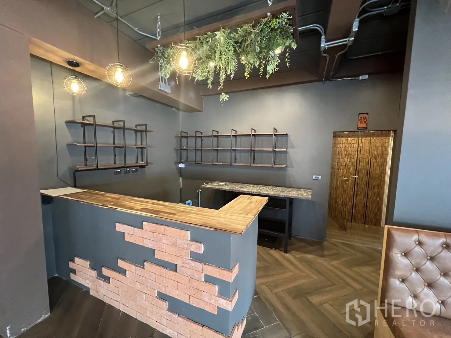 Retail Space for rent in Watthana, Bangkok - Bar counter corner with timber worktop, wall shelving and decorative hanging lights.