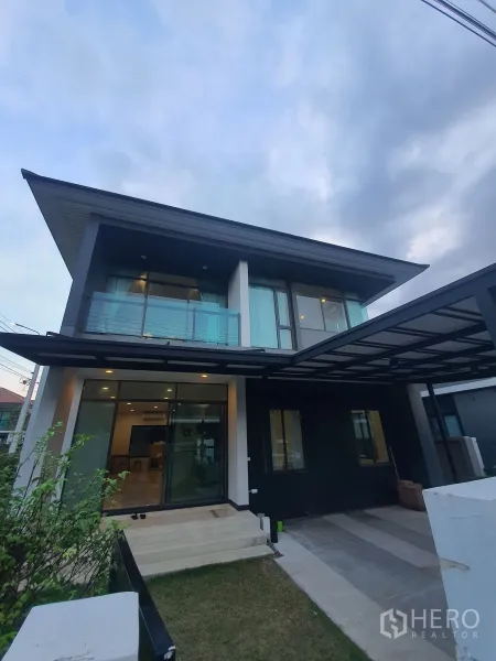 Detached House for rent in Bang Kapi, Bangkok - Angled exterior view showing glass balcony, sliding doors and covered carport.