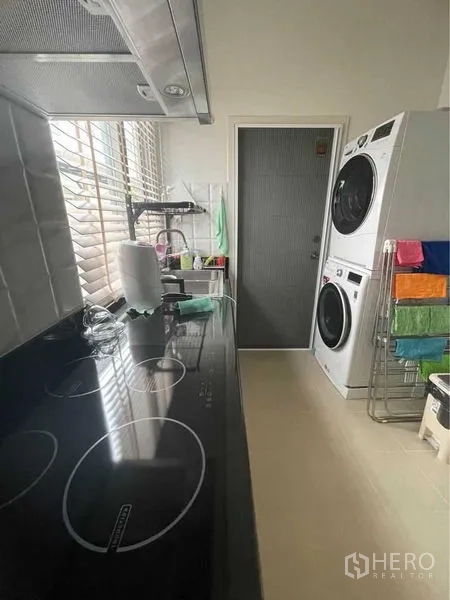 独立式住宅 出售在Lat Krabang, Bangkok - 厨房近景，电磁炉台面、百叶窗与叠放洗烘设备。