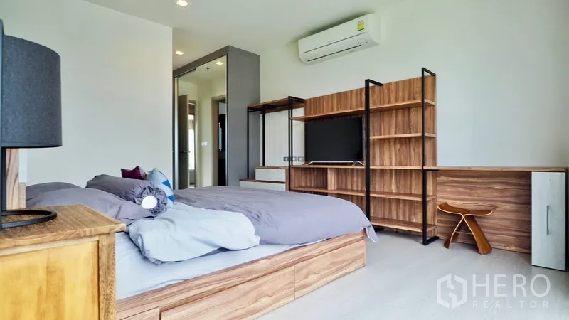 Condominium for rent in Khlong Toei, Bangkok - Spacious second bedroom with TV unit, shelving and air conditioning.