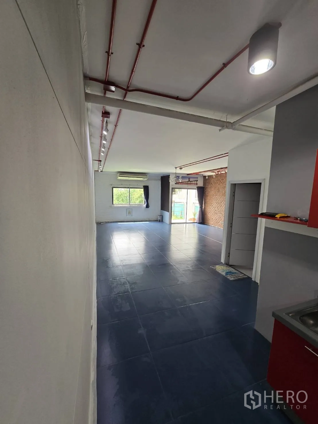 办公空间 出租在Watthana, Bangkok - 纵深视角的灵活工作区，大窗、轨道射灯、外露管线与砖墙。