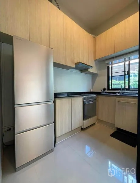 Townhouse for rent in Yan Nawa, Bangkok - Separate kitchen with light wood cabinetry, oven, range hood, and large fridge.