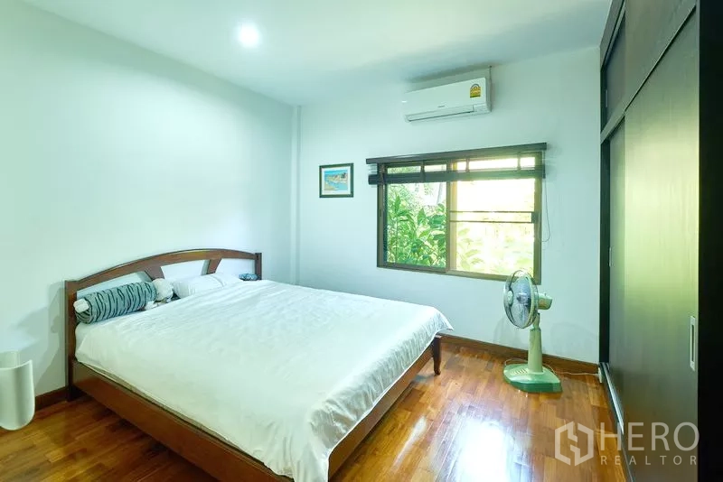 Detached House for sale in Bang Lamung, Chon Buri - Air-conditioned bedroom with double bed, built-in wardrobe, and window overlooking the garden.