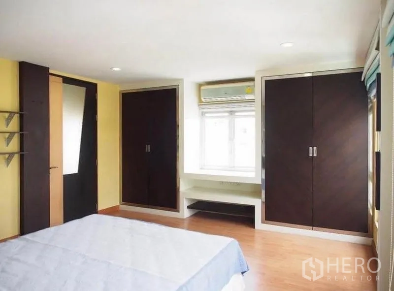 联排别墅 出租在Wang Thonglang, Bangkok - 卧室配双面嵌入式衣柜，窗边座位，空调与木地板。