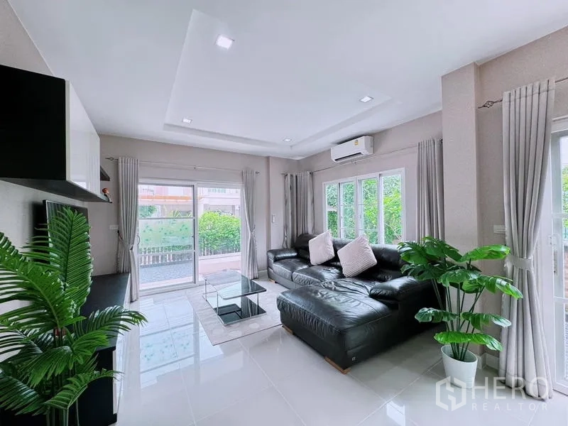 บ้าน ให้เช่าในPrawet, Bangkok - ห้องนั่งเล่นโปร่ง โซฟาหนังสีดำ ตู้ทีวี และหน้าต่างบานใหญ่