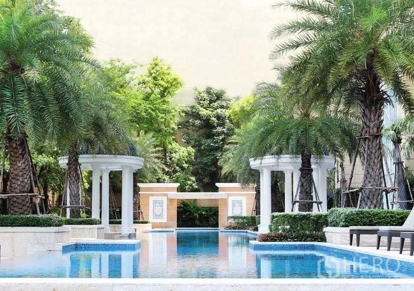 Condominium for sale in Watthana, Bangkok - Tropical pool zone framed by palms and white pavilions in the residence.