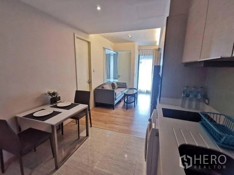 Condominium for rent or sale in Watthana, Bangkok - Open-plan kitchenette and living space with a two-seat dining table and natural light.