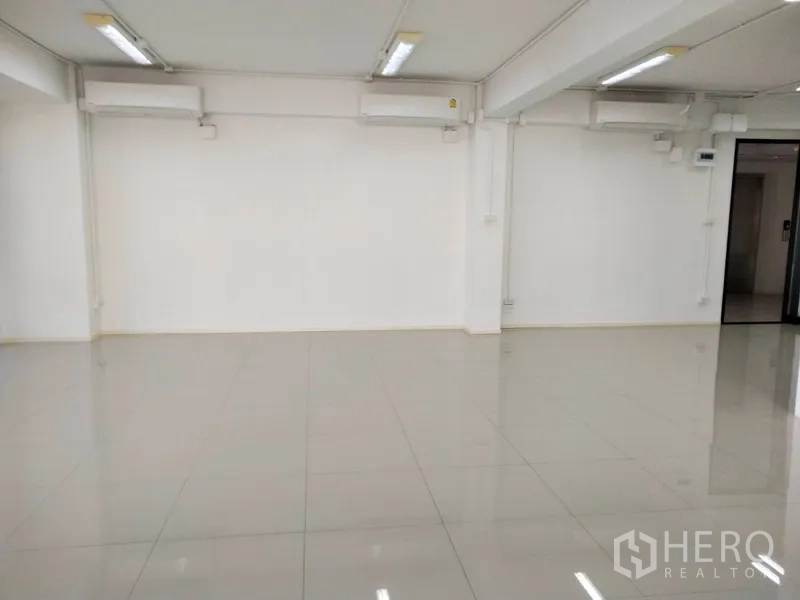 办公空间 出租在Bang Na, Bangkok - 装有分体空调与长条灯的办公室内部，地面光亮。