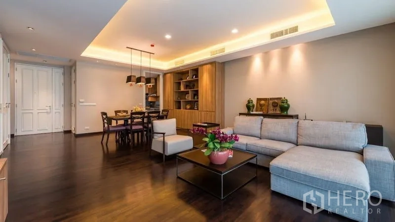 房间 出租在Pathum Wan, Bangkok - 宽敞客厅配L形沙发，天花灯带与定制展示柜。