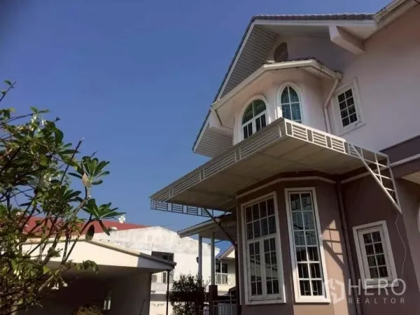 独立式住宅 出售在Phra Khanong, Bangkok - 二层立面特写：拱形窗、转角大飘窗与金属雨棚。