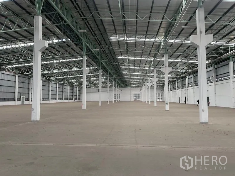 Factory for rent in Bang Sao Thong, Samut Prakan - Expansive warehouse interior with a high steel truss roof and rows of white columns.